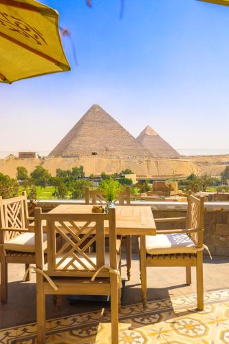 a wooden table and chairs with pyramids in the background at Onyx Pyramids Boutique Hotel in Cairo