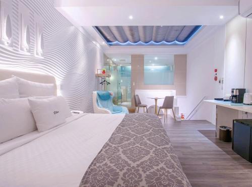 a bedroom with a large white bed and a kitchen at 168 Motel-Taoyuan in Taoyuan