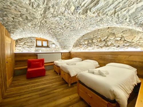 a row of beds in a room with a stone wall at La Mizoùn de Marguerito - Appartamento Ginestra in Acceglio