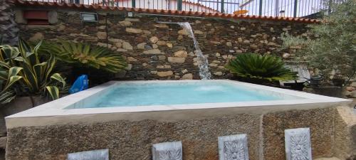 a hot tub with a waterfall in a garden at ROSA XVI - Garden Guest House in Vilar Torpim