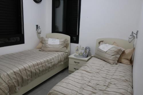 two beds sitting next to each other in a bedroom at דירה קטנה לנופש בלב גאולה יפיפייה ומטופחת in Jerusalem