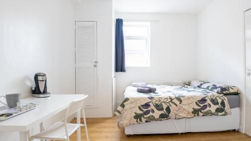 a white bedroom with a bed and a desk at Pebbles guest house room 3 in Southampton