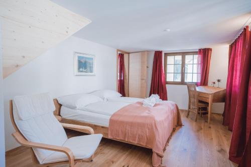 a bedroom with a bed and a chair and a desk at stettli resort in Parpan