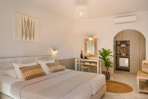 a white bedroom with a large bed and a desk at Makis Hotel in Skala Kefalonias