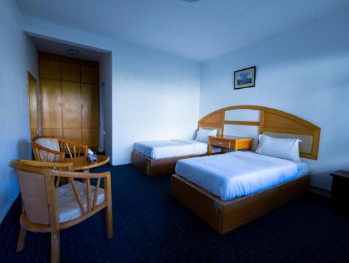 a hotel room with two beds and a chair at Hunza Marcopolo Inn Gulmit in Gulmit