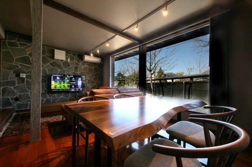 a dining room with a wooden table and chairs at Yufuin Kaze no Mori in Yufuin