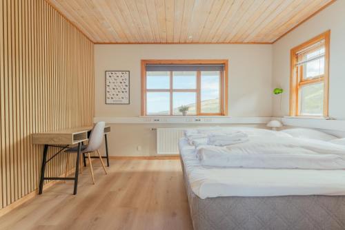 a bedroom with a large bed and a desk at Á Tromini Guesthouse in Tórshavn