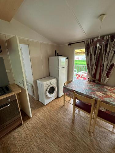 a small kitchen with a washing machine and a table at davorel mobil home in Les Mathes