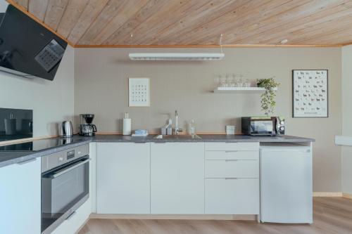 a kitchen with white cabinets and a wooden ceiling at Á Tromini Guesthouse in Tórshavn