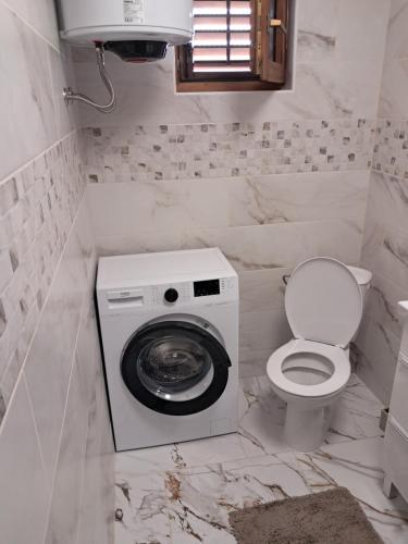 a bathroom with a washing machine and a toilet at Apartments Mara Bela in Karlobag