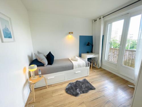 une chambre avec un lit et une grande fenêtre dans l'établissement Le FRIENDLY, proche PARIS, à Villeneuve-la-Garenne