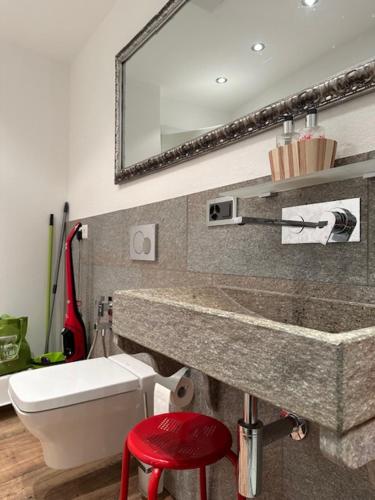 a bathroom with a sink and a toilet and a red stool at Appartament ReLaax in Laax