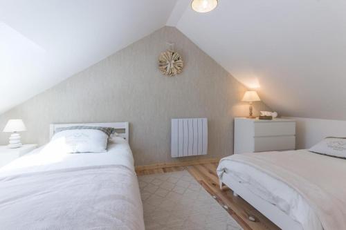 ein Schlafzimmer im Dachgeschoss mit 2 Betten und einer Uhr an der Wand in der Unterkunft La Maison du Fort in Banneville-la-Campagne
