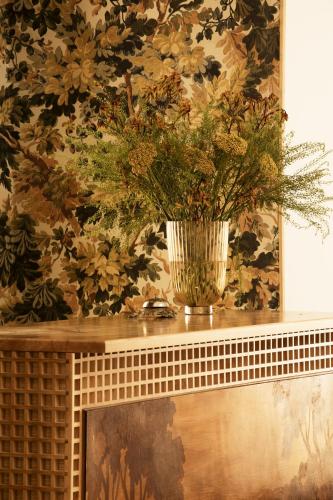 a vase on top of a fireplace with a floral wallpaper at Casa Pizarro Hotel in Cáceres