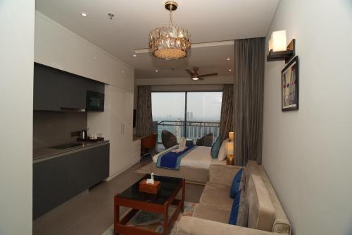 a living room with a couch and a bed and a kitchen at Hotel Livbox at Supernova in Noida