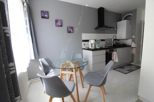 une petite cuisine avec une table et des chaises en verre dans l'établissement Studio Nancy Thermal Studio en petite résidence, à Nancy