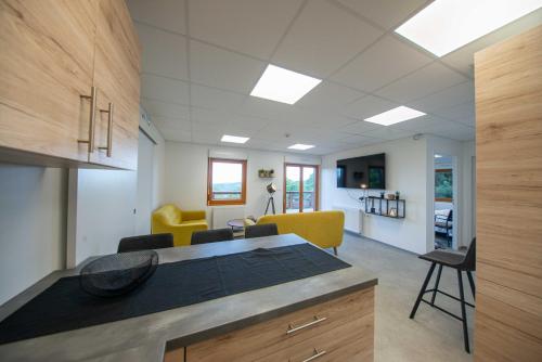 an open kitchen and living room with yellow chairs at Le chalet de l'amicale in Vagney