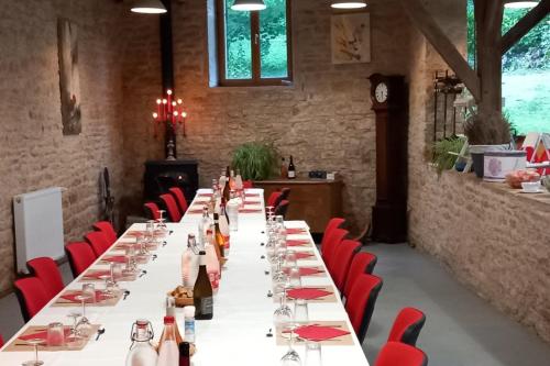 a long table with wine bottles and red chairs at Chateau de Joudes Suite de la Baronne in Joudes