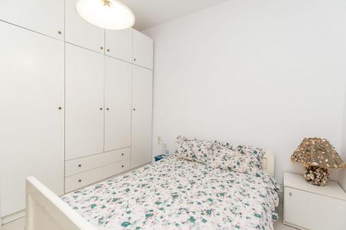 a white bedroom with a bed and white cabinets at Palm Tree 1 in Karianí