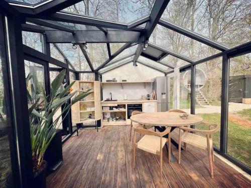 a conservatory with a table and chairs and a kitchen at Twee heerlijke Boomhutten in de natuur, Amsterdam in Nigtevecht