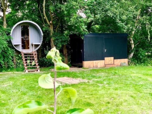 a small shed in a yard with a tree at Twee heerlijke Boomhutten in de natuur, Amsterdam in Nigtevecht