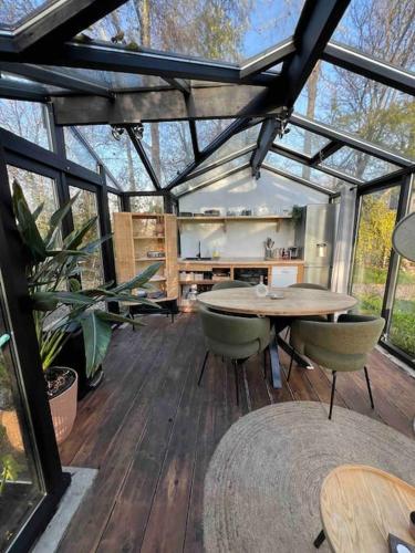 a glass house with a table and chairs in it at Twee heerlijke Boomhutten in de natuur, Amsterdam in Nigtevecht