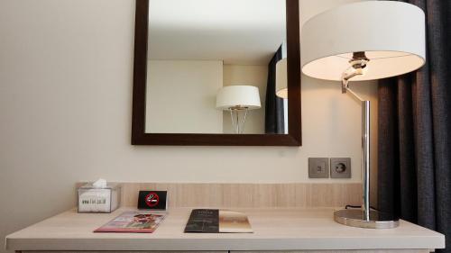 a desk with a lamp and a mirror on a wall at Louis Kienne Hotel Pandanaran in Semarang