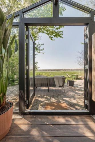 a sliding glass door leading to a patio with a chair at Twee heerlijke Boomhutten in de natuur, Amsterdam in Nigtevecht