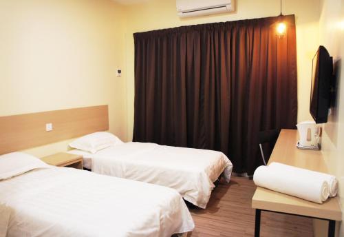 a hotel room with two beds and a television at No.31 Maple Inn in Simpang Ampat