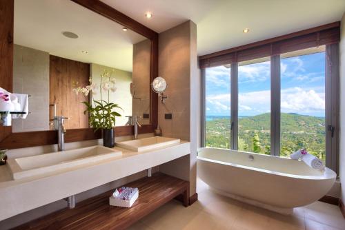 a bathroom with two sinks and a tub with a window at Baan Grand Vista - Panoramic Sea View 5 Bed Pool Villa in Bophut