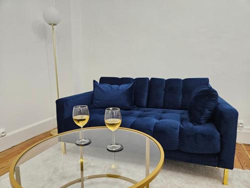 - un salon avec un canapé bleu et deux verres de vin dans l'établissement Suite chic, contemporaine au pied de la Cathédrale, à Vienne