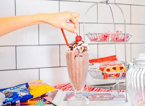 a woman stirring a milkshake with a cherry on top at Spice Motel Okinawa in Kitanakagusuku