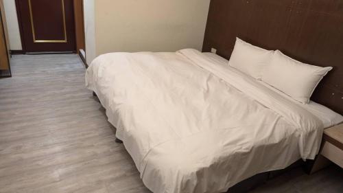a bed with white sheets and pillows in a room at Waugh Den Business Hotel in Taichung