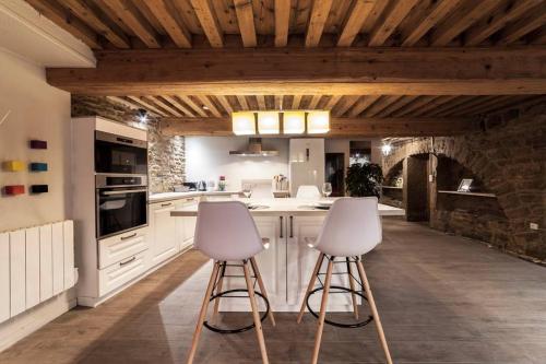 une cuisine avec deux tabourets dans une cuisine avec un mur en pierre dans l'établissement La grotte de la Baleine du Vieux Lyon AIL, à Lyon
