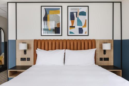 a bedroom with a large bed with two pictures on the wall at voco Belfast by IHG in Belfast