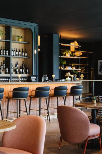 a restaurant with a bar with chairs and tables at voco Belfast by IHG in Belfast