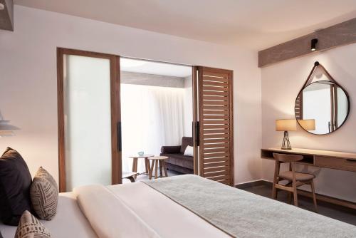 a bedroom with a bed and a desk and a mirror at Atlantica Caldera Palace in Hersonissos