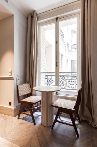 une table et deux chaises dans une pièce avec une fenêtre dans l'établissement Stylish Apartment - 1BR-4P - Vendôme Square, à Paris