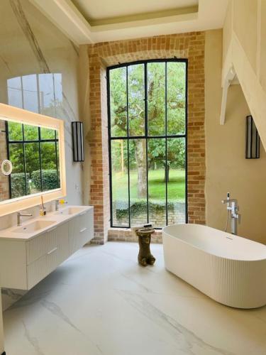 une grande salle de bains avec deux lavabos et une grande fenêtre dans l'établissement Château de Beauchamp- La chapelle de Guinchay, à La Chapelle-de-Guinchay