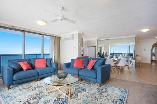 a living room with blue couches and red pillows at Peninsula Apartments managed by Gchs in Gold Coast