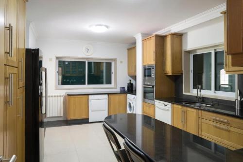 a kitchen with wooden cabinets and a black counter top at Lavanda Village Cascais - Villa Jasmim I in Cascais