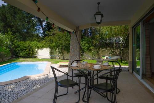 a patio with a table and chairs next to a swimming pool at Lavanda Village Cascais - Villa Jasmim I in Cascais