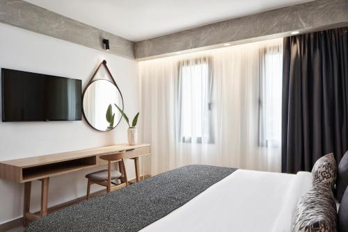 a hotel room with a bed and a desk and a mirror at Atlantica Caldera Palace in Hersonissos