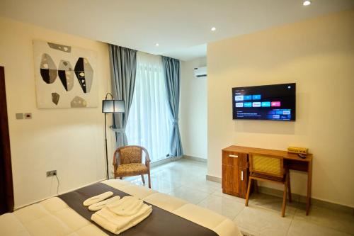 a bedroom with a bed and a desk and a tv at AIDEN HOMES AND APARTMENTS HOTEl in Koforidua