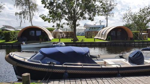 a small boat on the water with some tents at Glamping at the water, close to Amsterdam in Aalsmeer