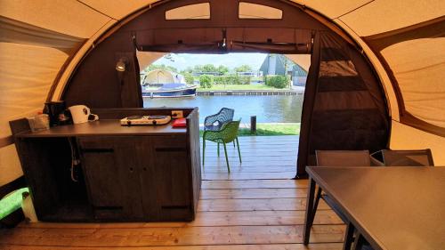 a tent with a kitchen and a view of the water at Glamping at the water, close to Amsterdam in Aalsmeer