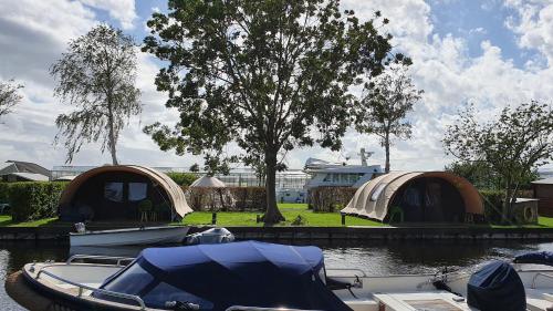 a group of tents and a boat in the water at Glamping at the water, close to Amsterdam in Aalsmeer
