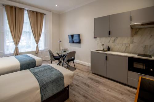 two beds in a room with a kitchen and a table at New Kent Apartments in London