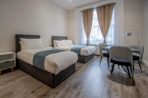 a bedroom with two beds and a table and chairs at New Kent Apartments in London