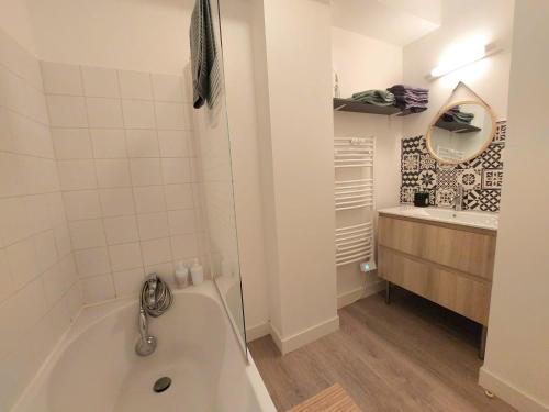 une salle de bain blanche avec une baignoire et un lavabo dans l'établissement Duplex en centre-ville, à Morlaix